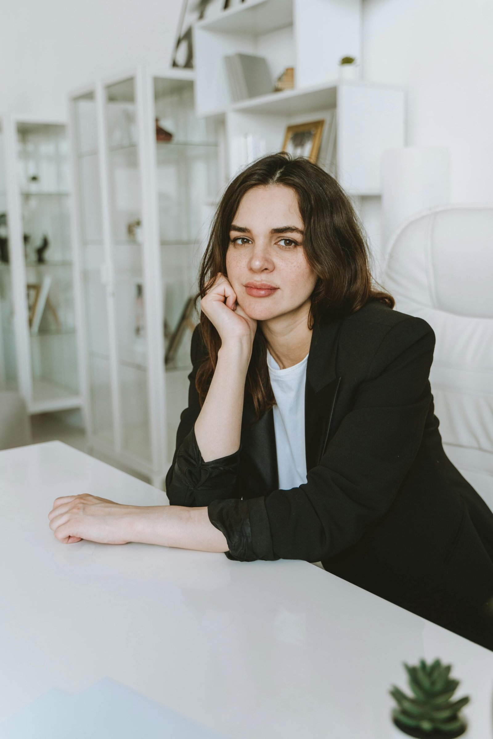 Portrait of a businesswoman sitting confidently at her desk in a modern white office setting.